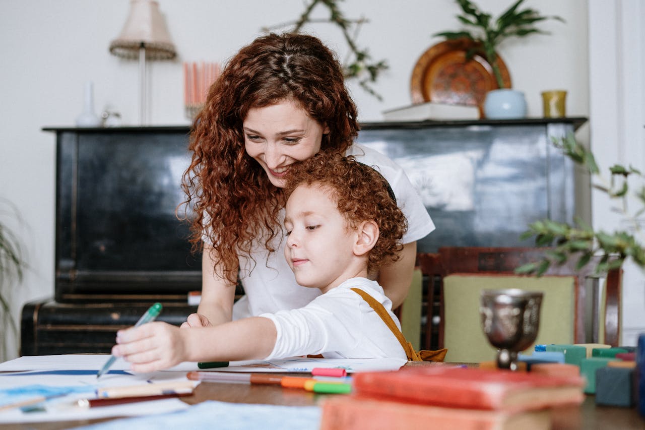 A loving mother and her child enjoy drawing together at home, fostering creativity and family bonding.